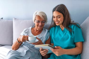 Friendly relationship between smiling caregiver in uniform and elderly woman